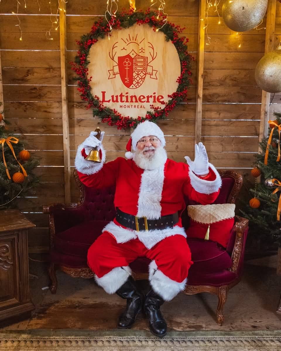 Le Père Noël accueille des enfants devant sa cabane de bois lors d'un événement extérieur.