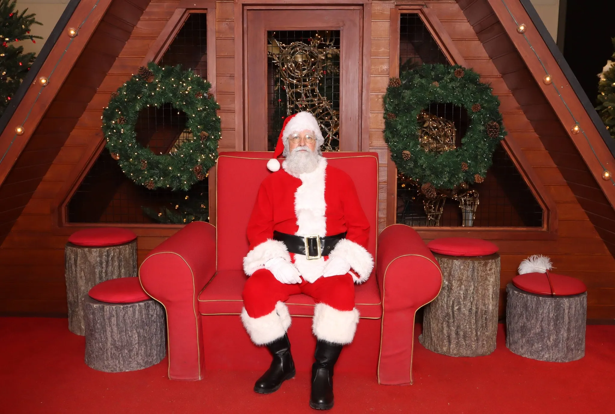 Le Père Noël dans son fauteuil rouge, au salon d'un chalet décoré.