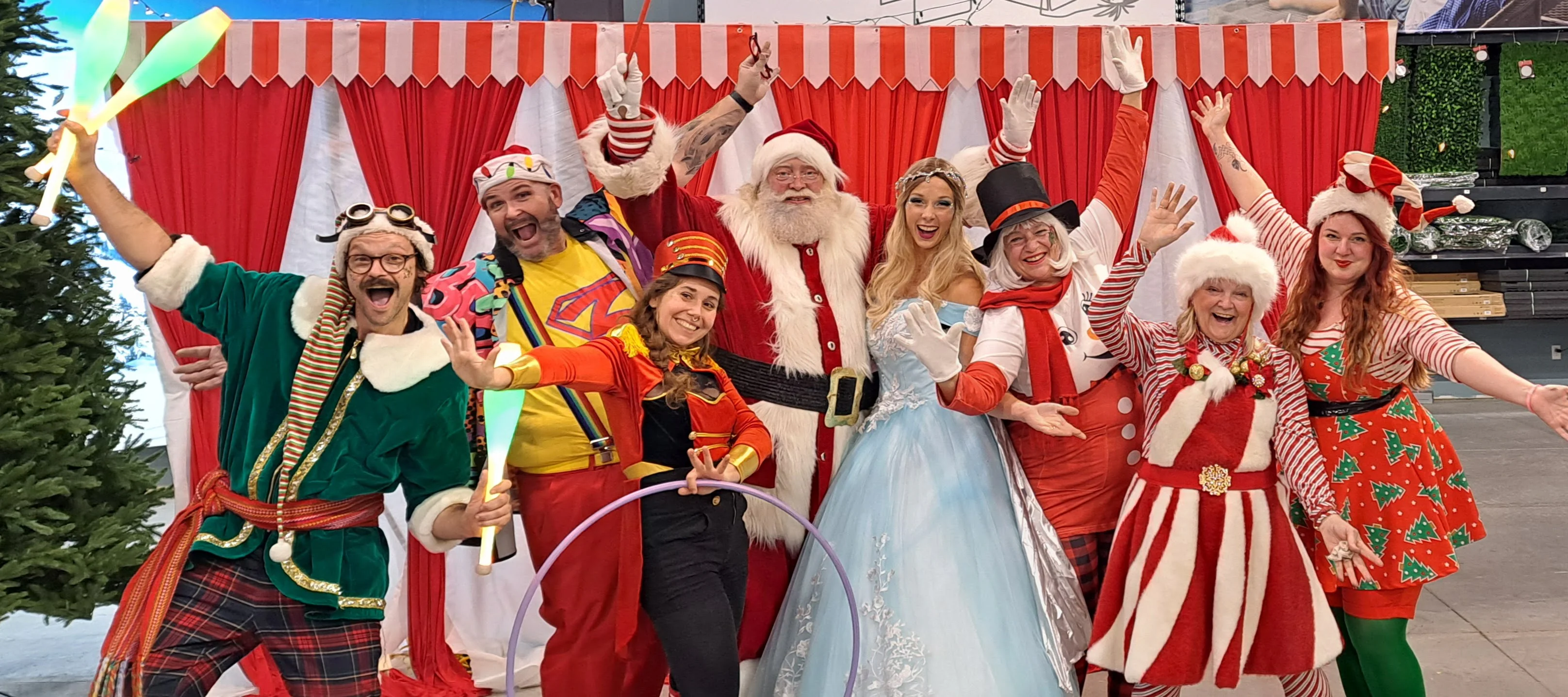 La troupe JDO au complet devant un chapiteau rayé rouge et blanc, dix artistes bras levés.
