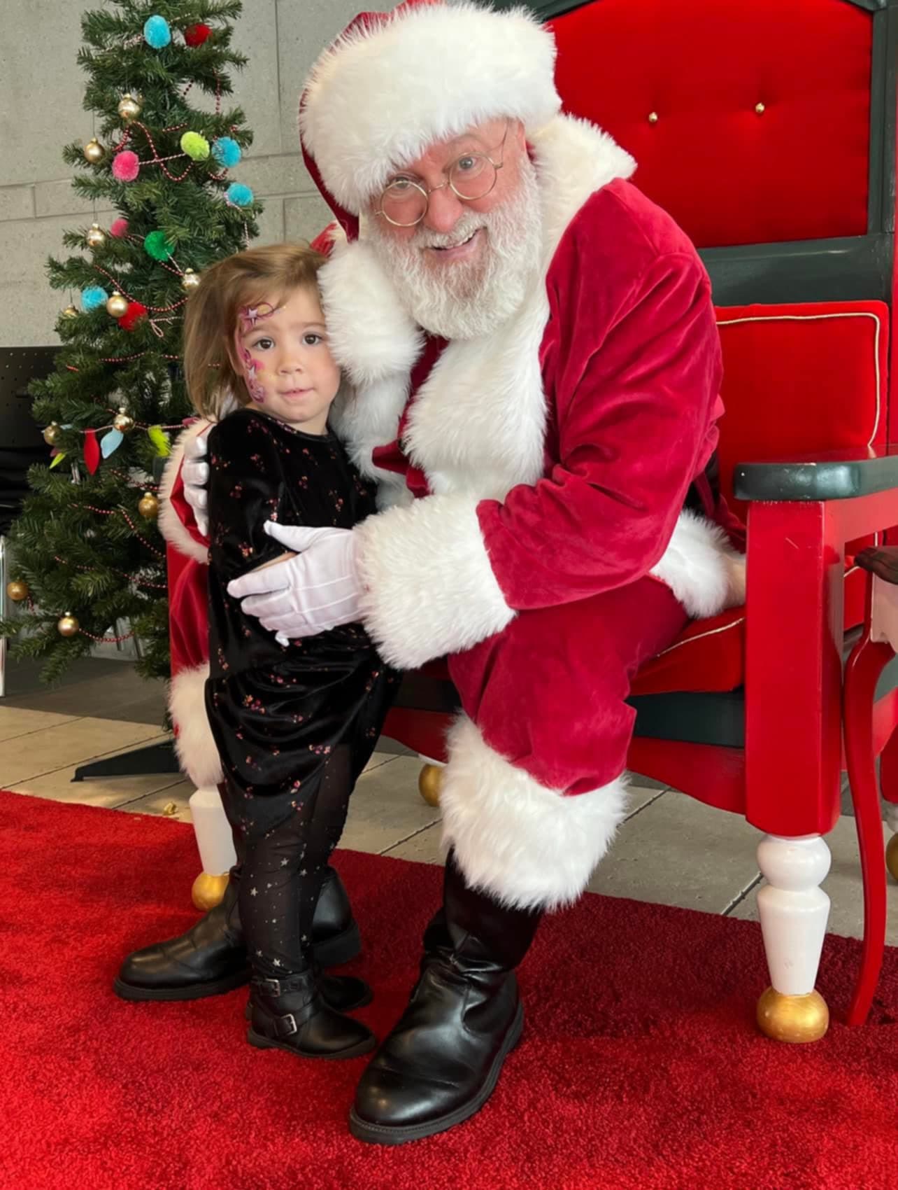 Le Père Noël Yvan accroupi auprès d'une fillette.