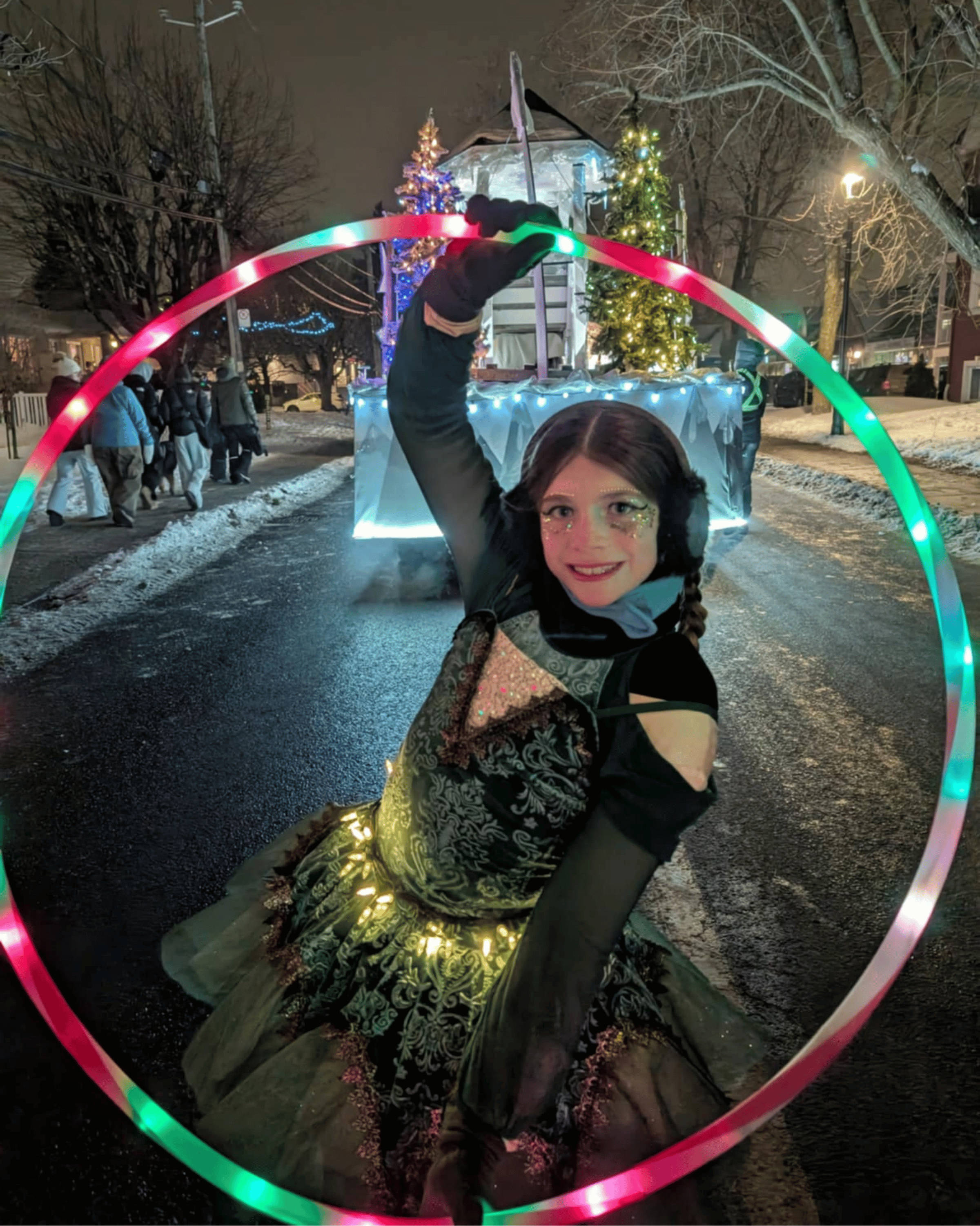 Performeuse au cerceau lumineux pendant la parade de nuit.