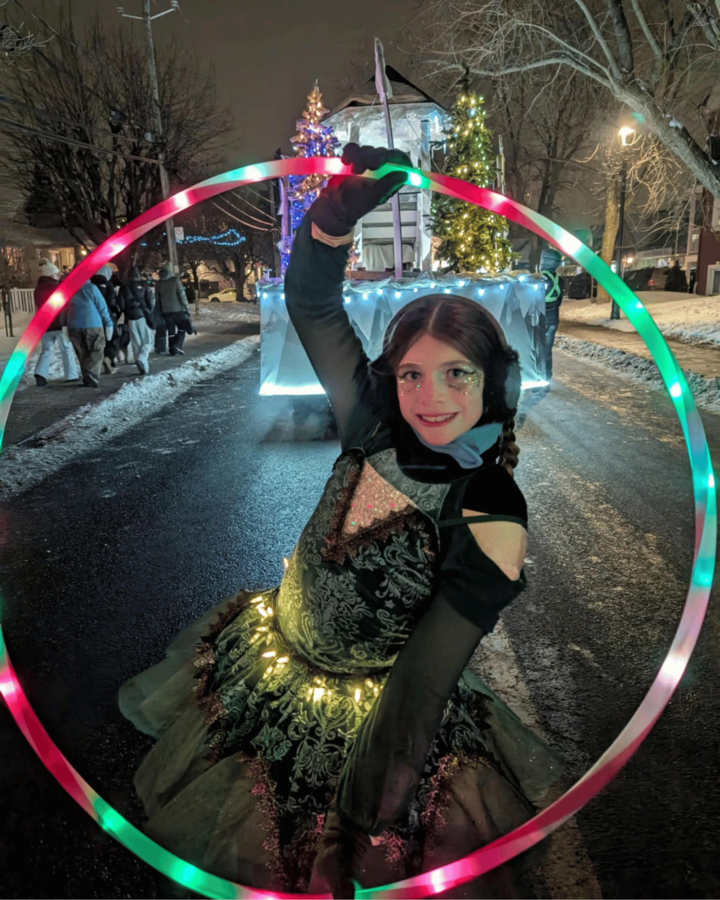 Performeuse au cerceau lumineux pendant la parade de nuit.