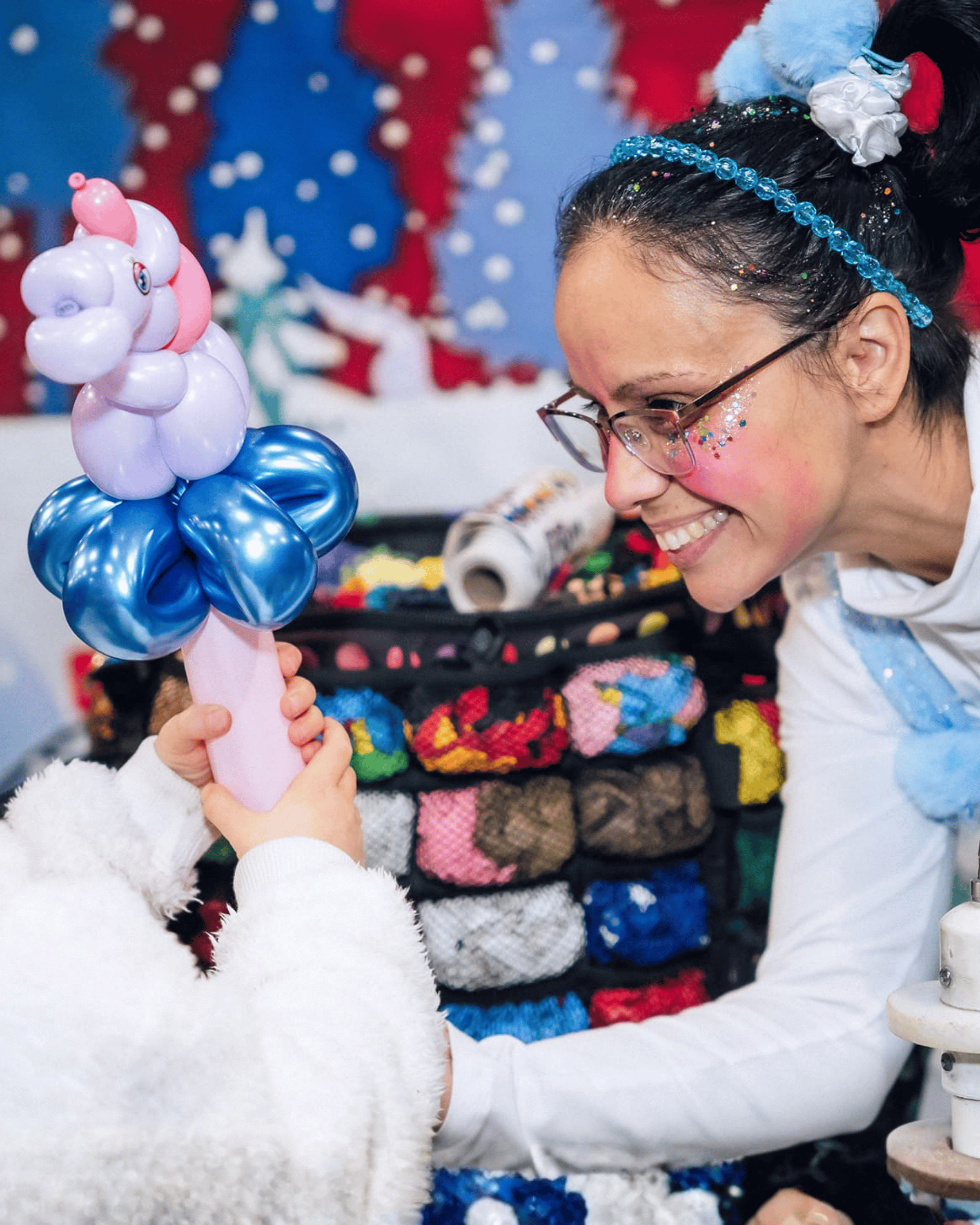 Une sculptrice de ballons présente ses créations devant une bannière de Noël.