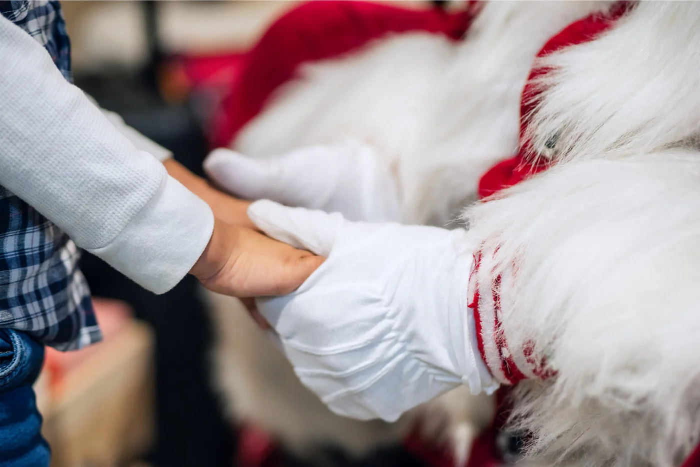 La main d'un enfant tenue dans les mains gantées du père Noël.